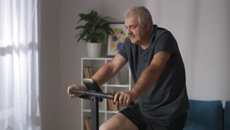 Retrato-De-Una-Persona-De-Mediana-Edad-Entrenando-En-Bicicleta-Estática-En-Casa-Manteniéndose-En-Forma-Y-Perdiendo-Peso-Ejercicio-Cardiovascular-Para-La-Salud-Y-La-Buena-Sensación